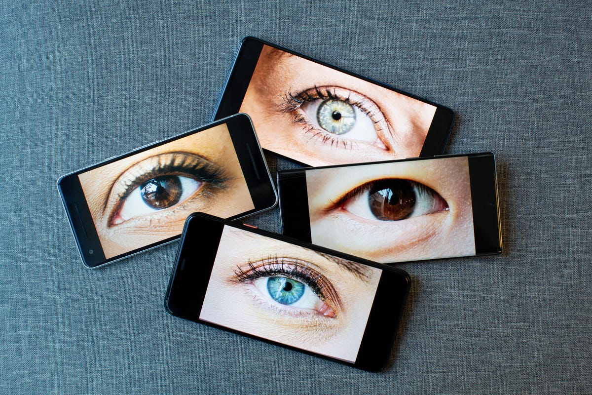 Four smartphones, each with an eyeball staring at you
