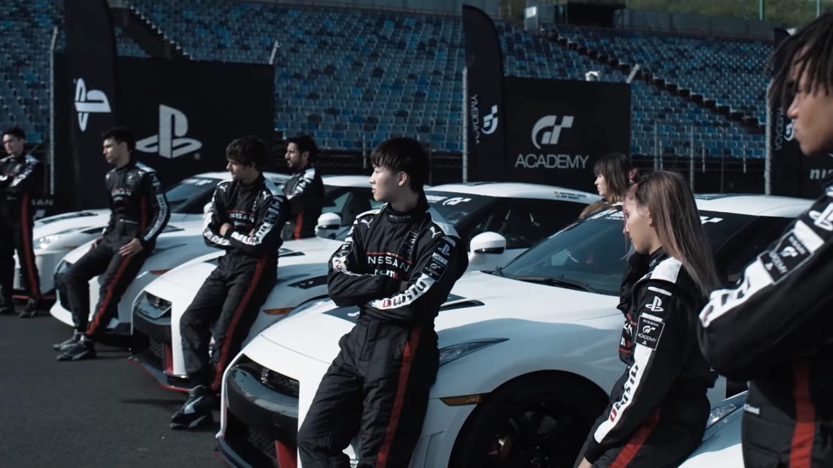 race car drivers in black uniforms lean on white cars on a grid