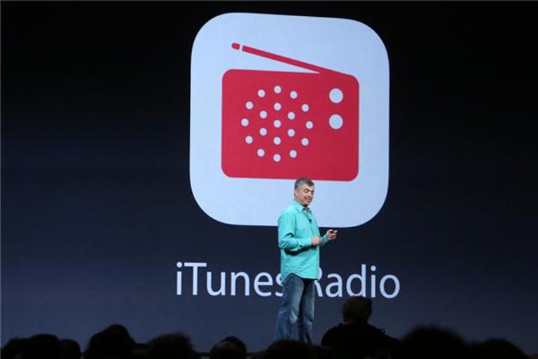 Apple executive on a stage with iTunes Radio's logo projected behind him.