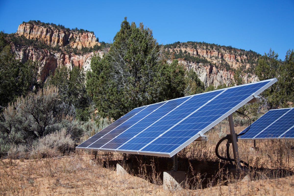 Ground-mounted solar panels in front of bluffs.