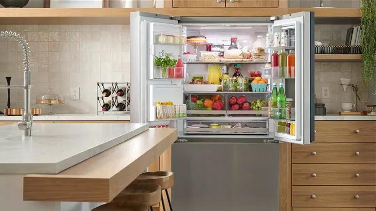 An LG refrigerator is open, showing plenty of produce and other food products inside.