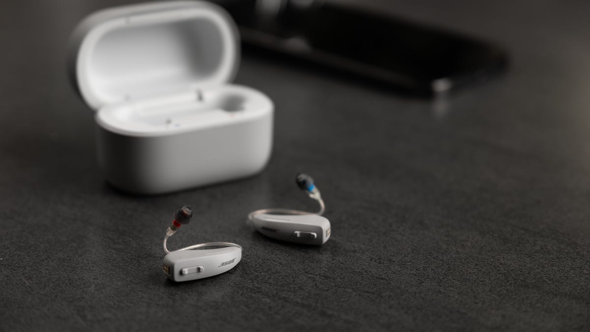 Two small hearing aids out of their case sitting on a desk