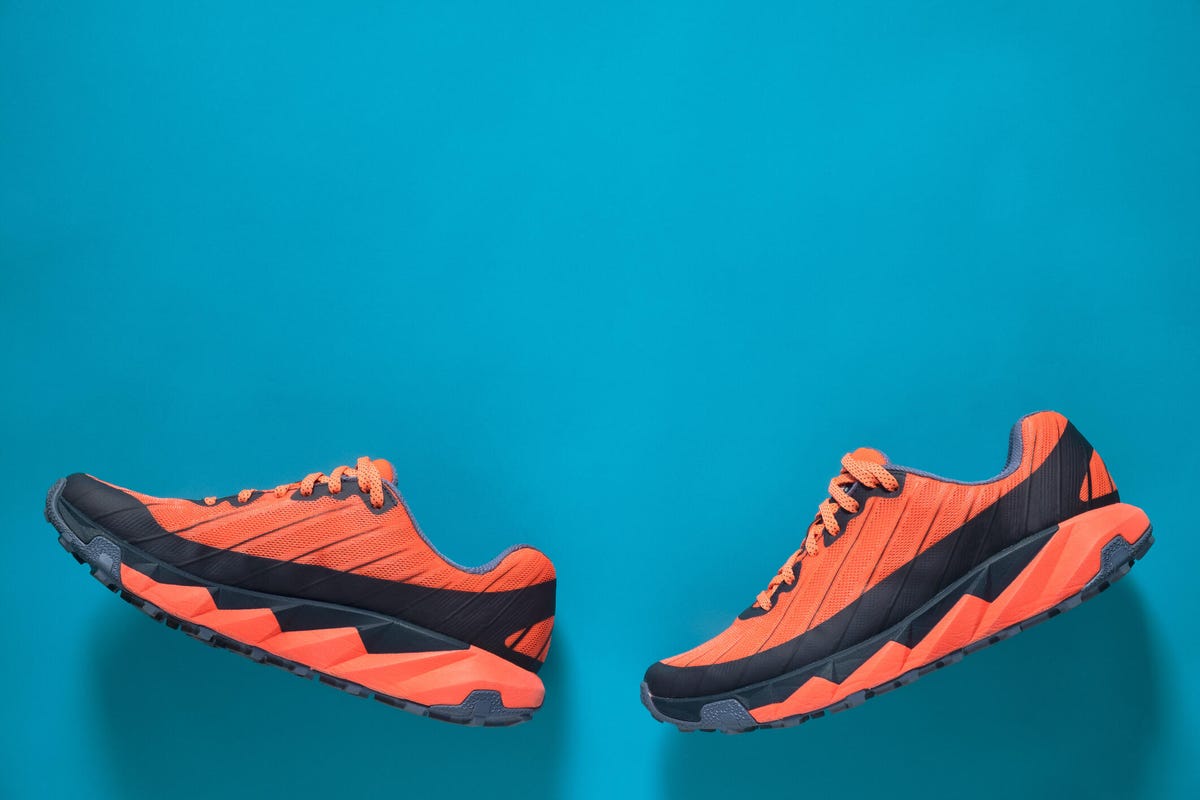Orange and black running shoes on a bright blue background