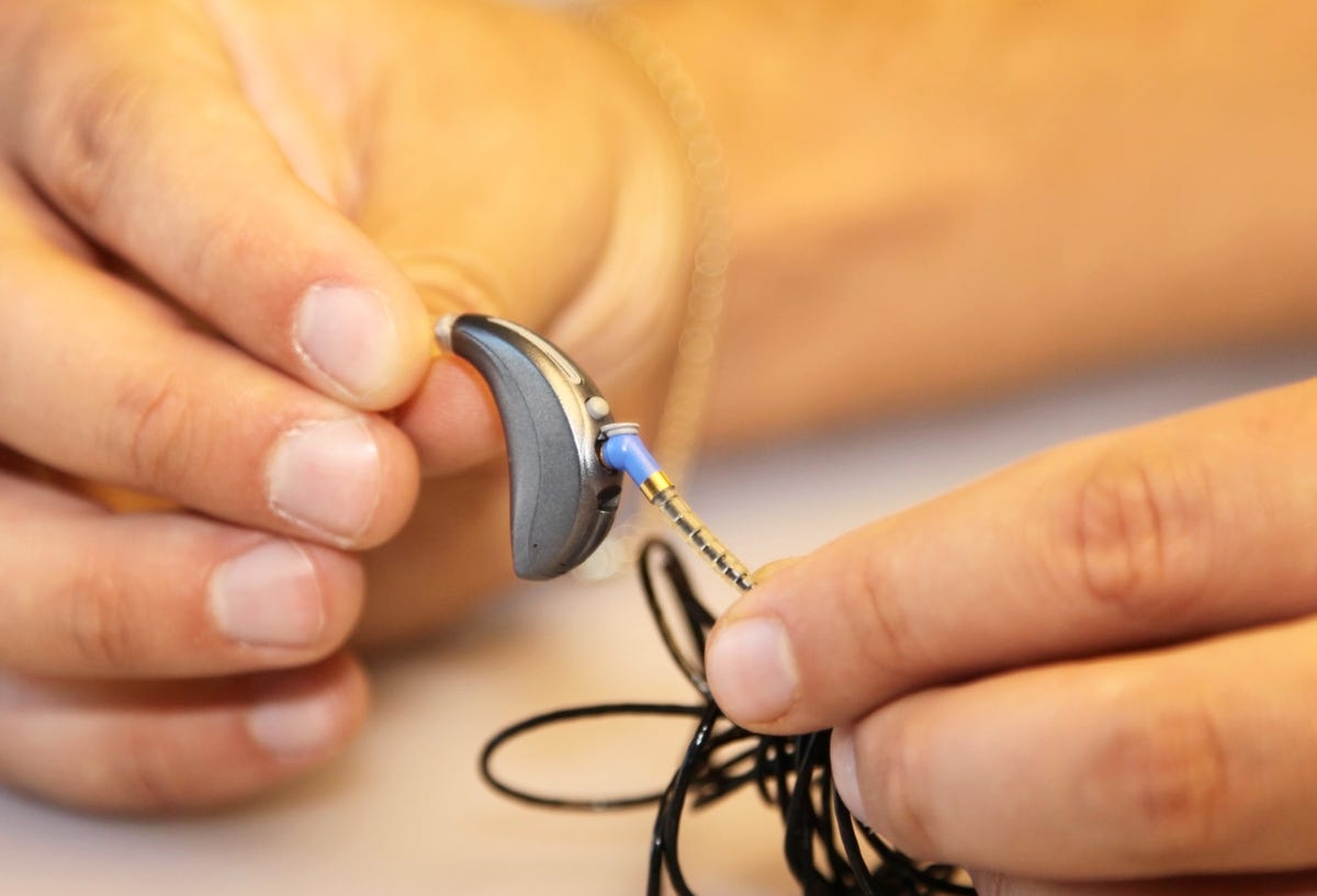 Adjusting volume on a modern hearing aid.