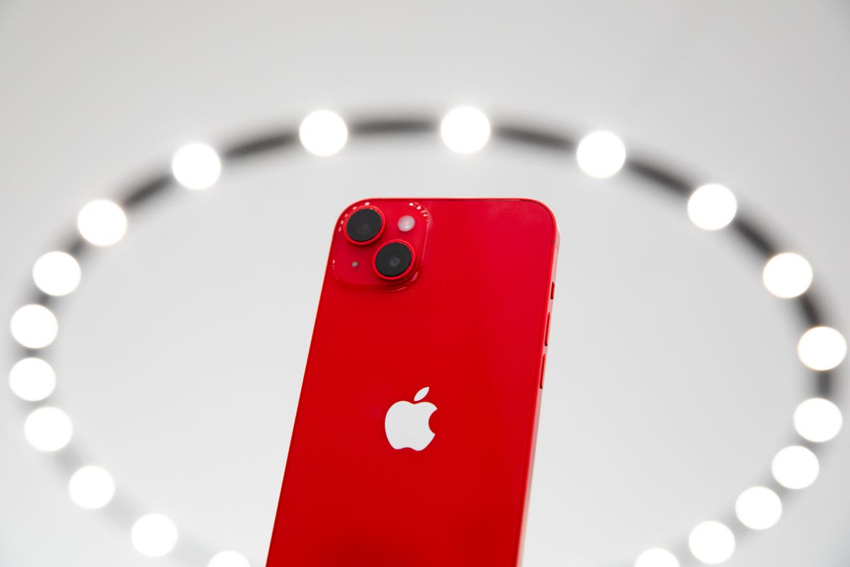 Red iPhone 14 surrounded by a ring of lights