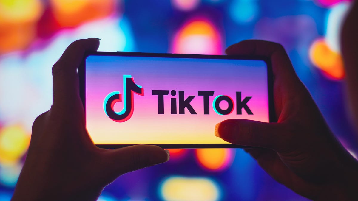 A smartphone being held horizontally with the TikTok logo appearing on the screen