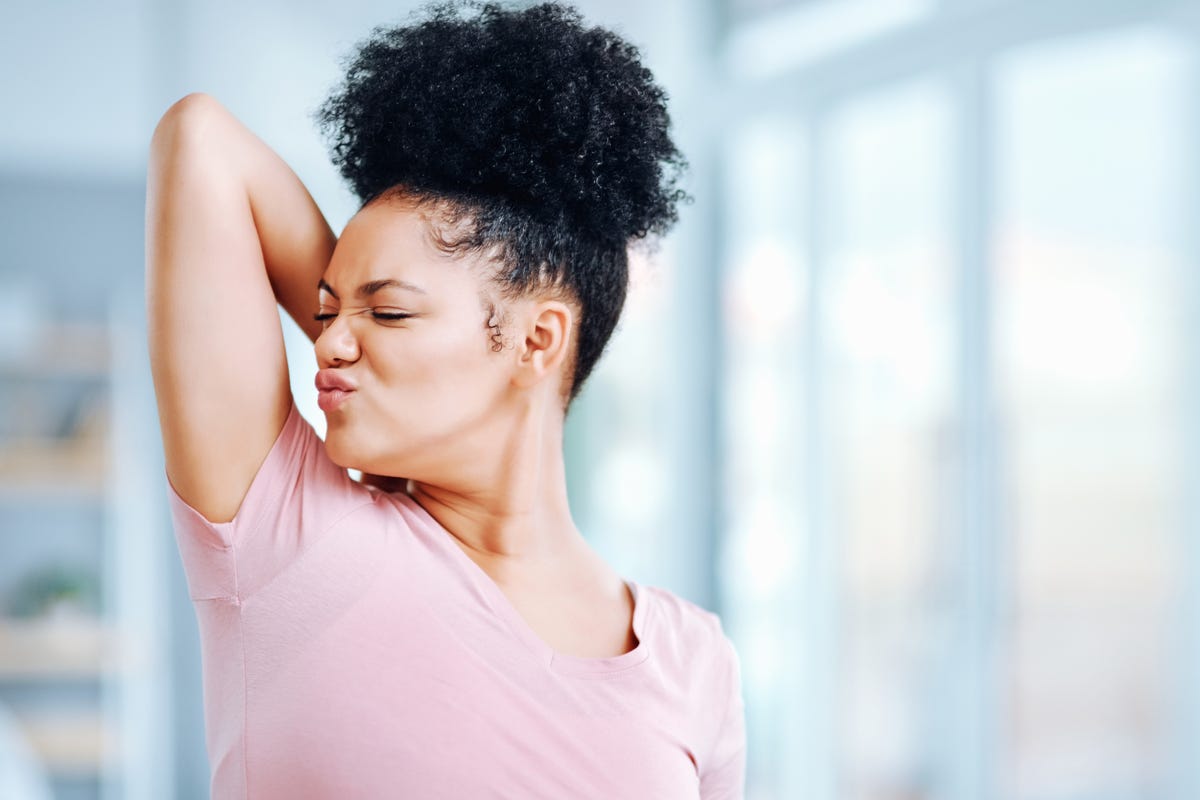 Woman raising her right arm and sniffing her armpit