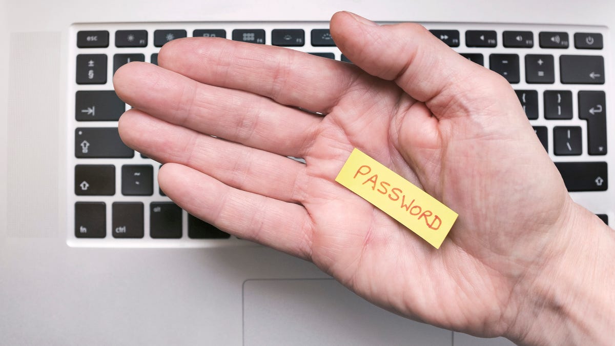 hand holding a note that says PASSWORD above a keyboard