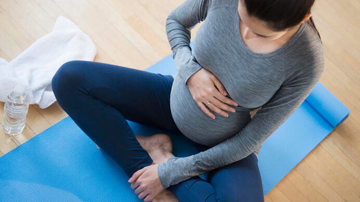 pregnant woman sitting on yoga mat