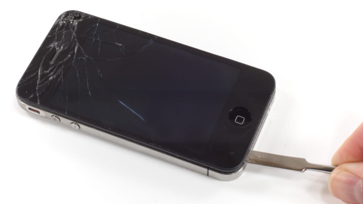 An iPhone 4 with a cracked screen being repaired.