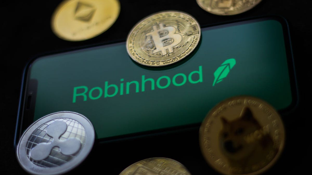 The Robinhood logo on a phone screen, surrounded by coins representing cryptocurrency