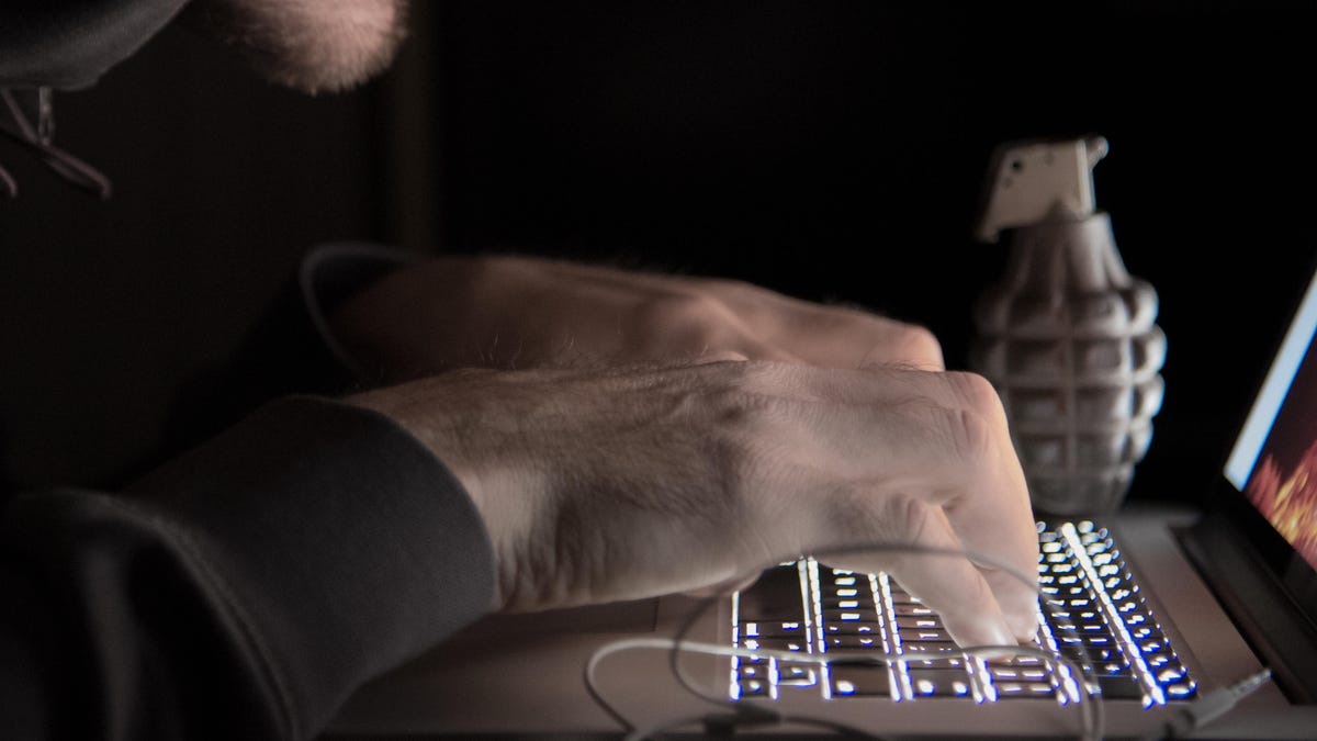Midsection Of Computer Hacker Using Laptop In Darkroom