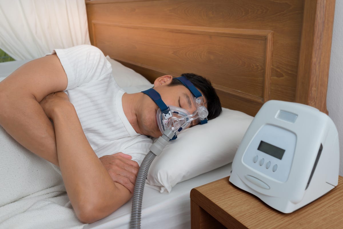 Young man wearing a CPAP mask in bed