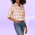 A woman wearing an Amazon Essentials classic-fit long-sleeve plaid flannel shirt is displayed against a gradient lavender background.