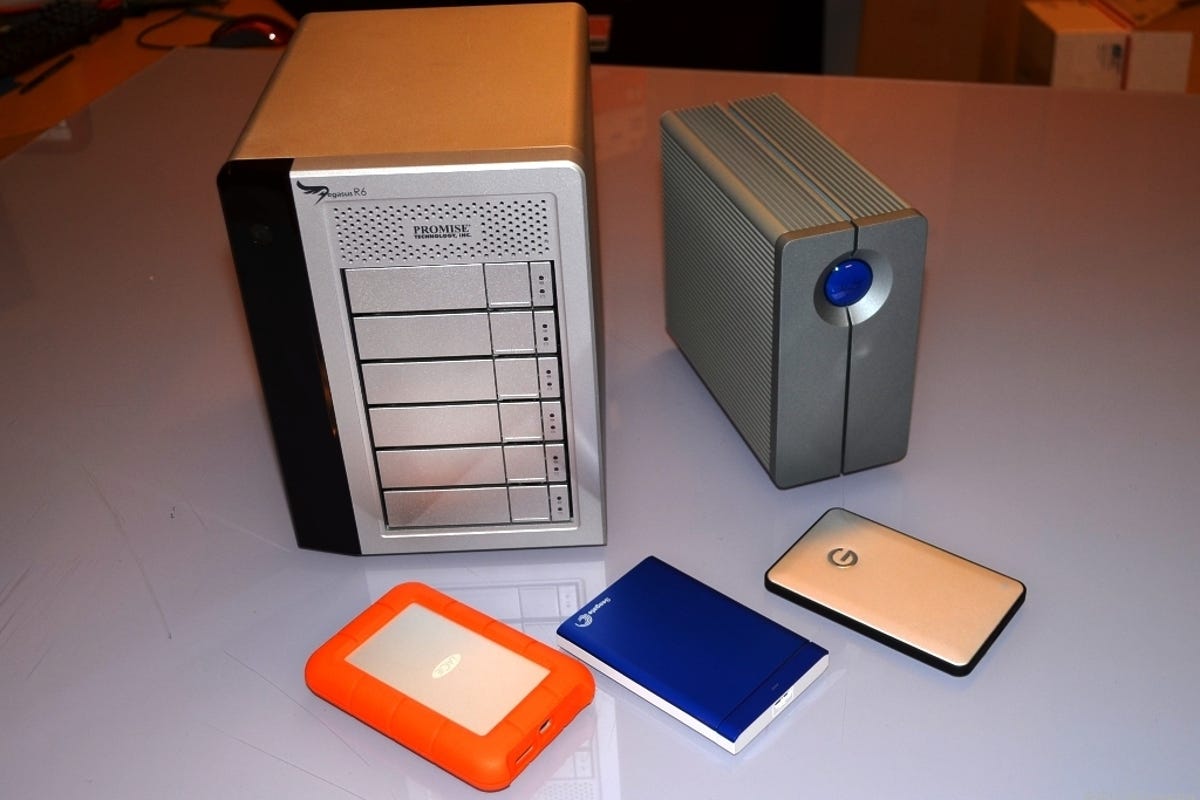 Two multiple-bay external drives next to three portable drives.