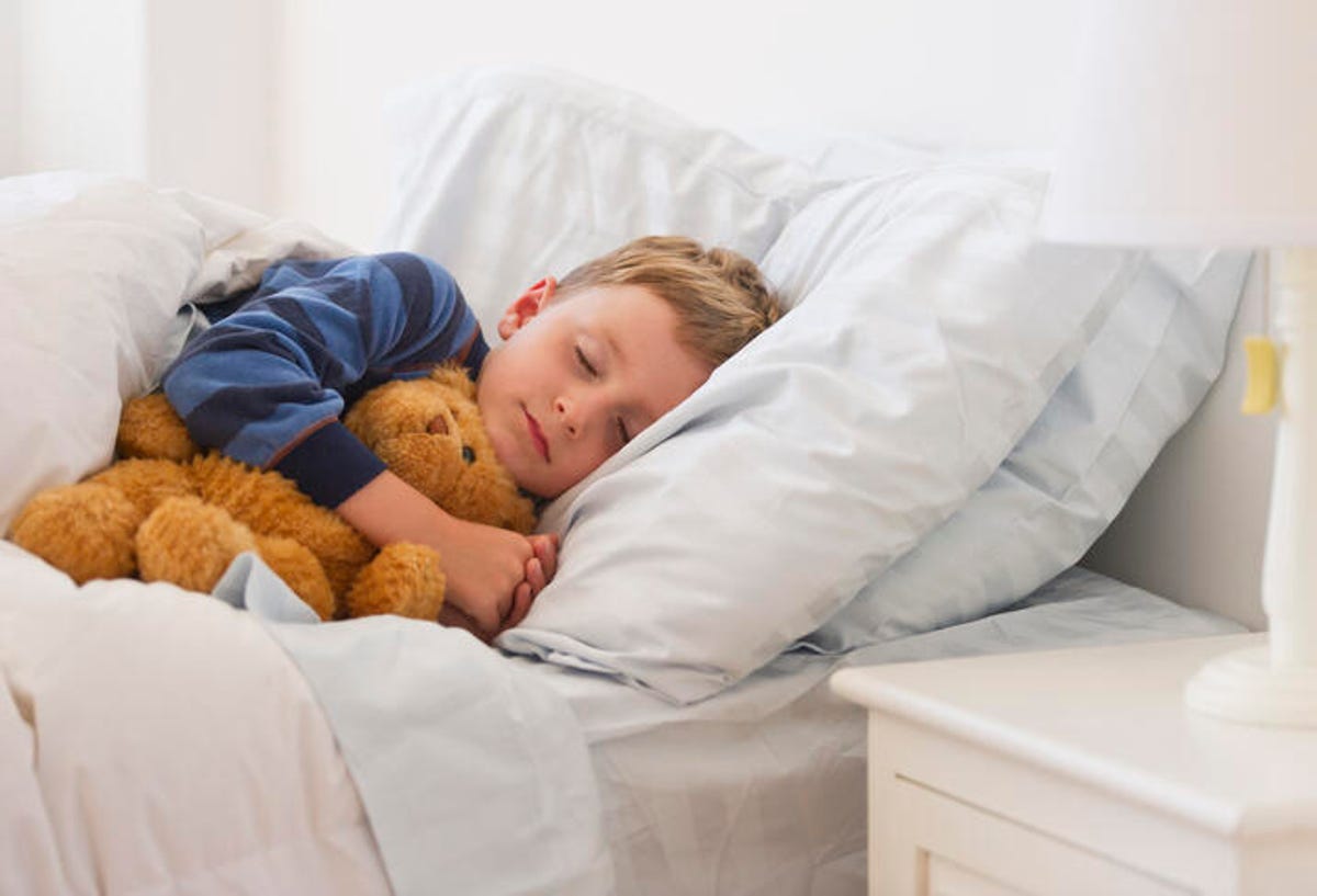 child sleeping in bed with a teddy bear