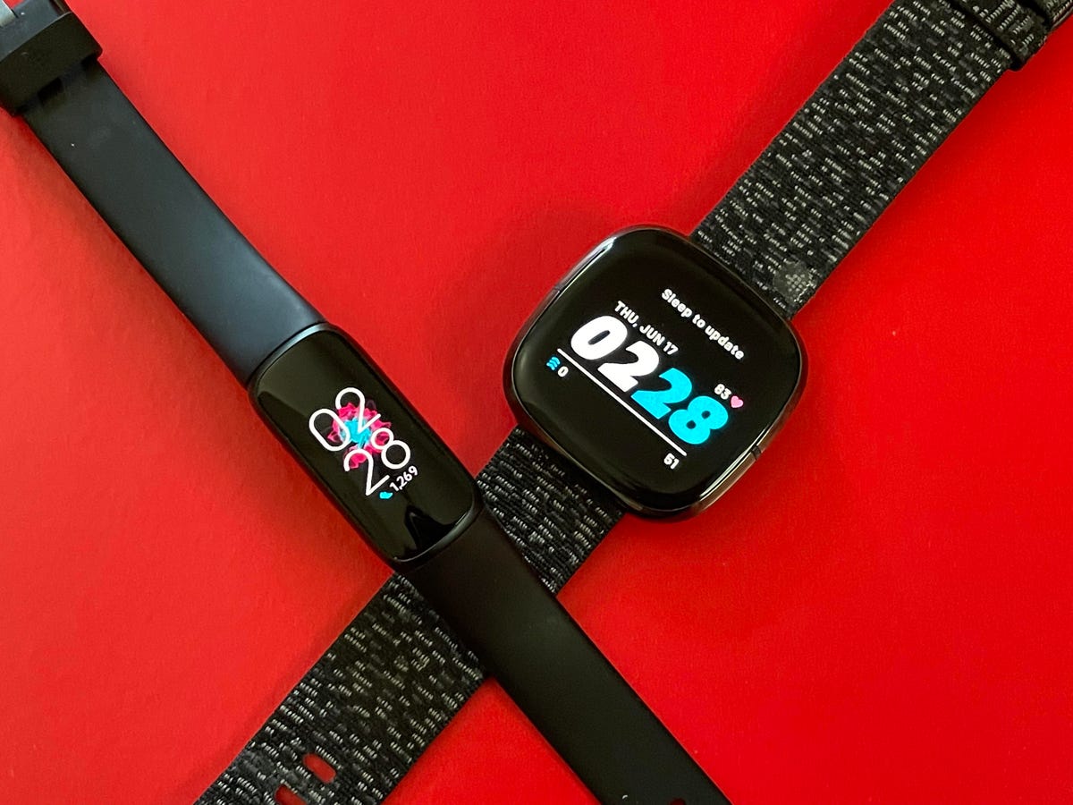 The narrow Luxe and squarer Fitbit Sense with their bands crossed