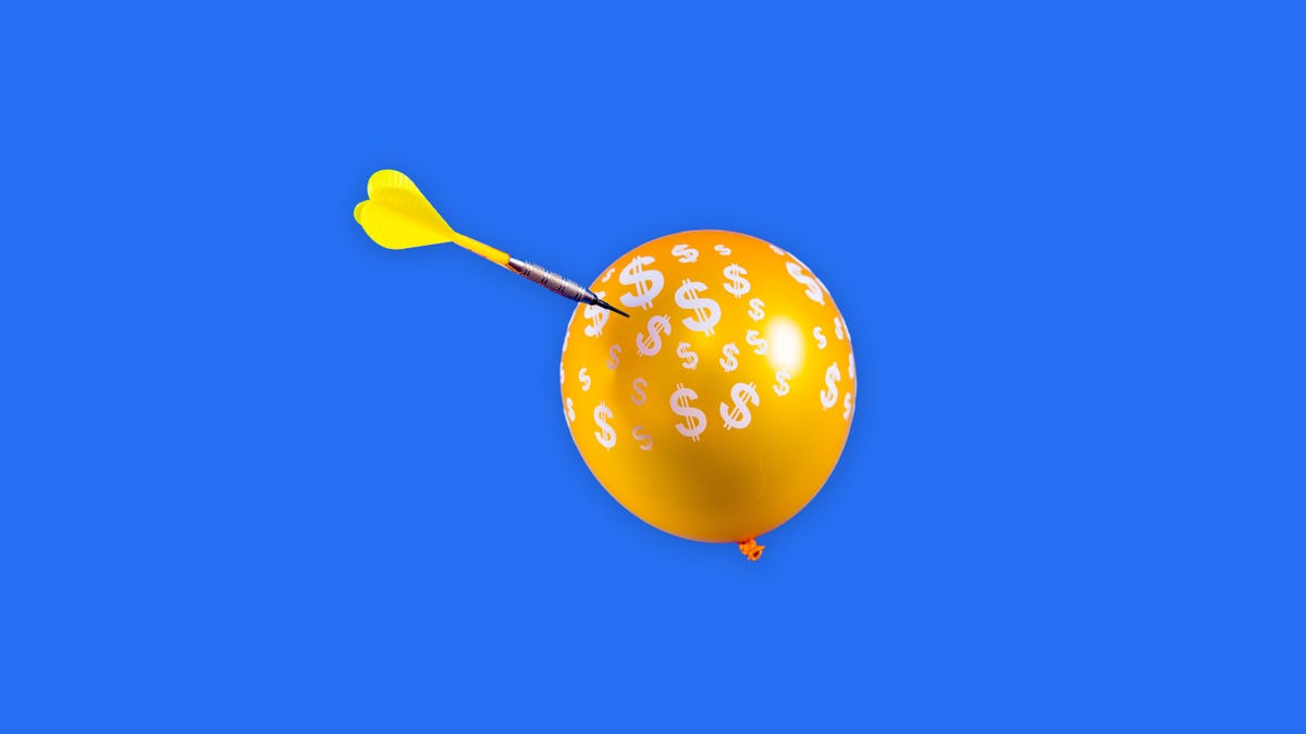 An inflated balloon with dart about to puncture it