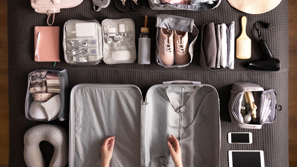 Open, empty suitcase with travel items arranged neatly around it