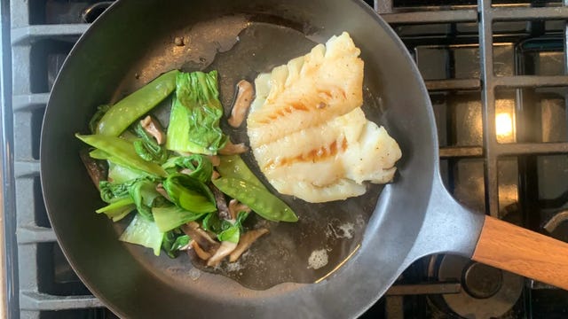 fish and veggies being heated in pan