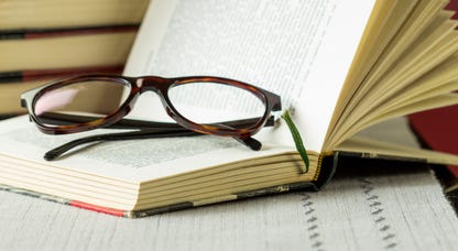 Pair of reading glasses resting in an open book.
