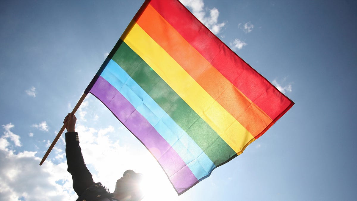 A man waves a rainbow flag
