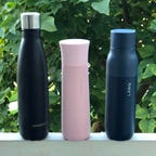 Three self-cleaning water bottles outside.