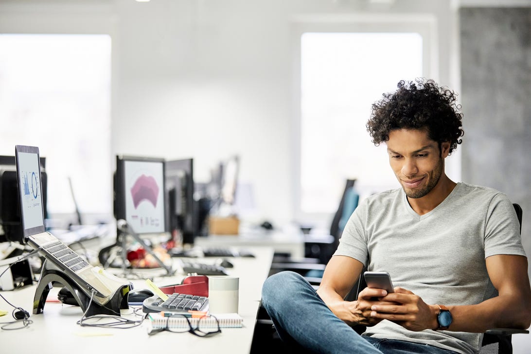 Man sitting at a desk using a smartphone.