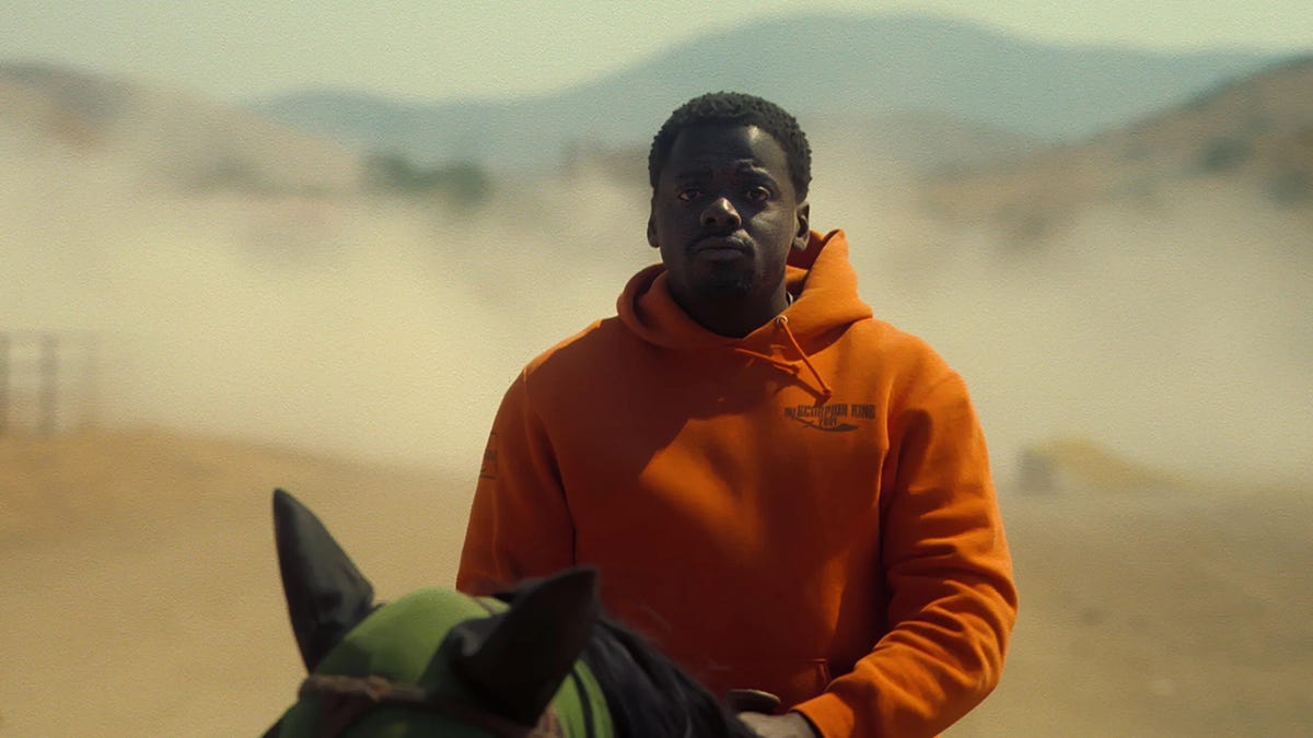 Daniel Kaluuya, in Nope, rides horseback with a dusty desert swirling behind him.