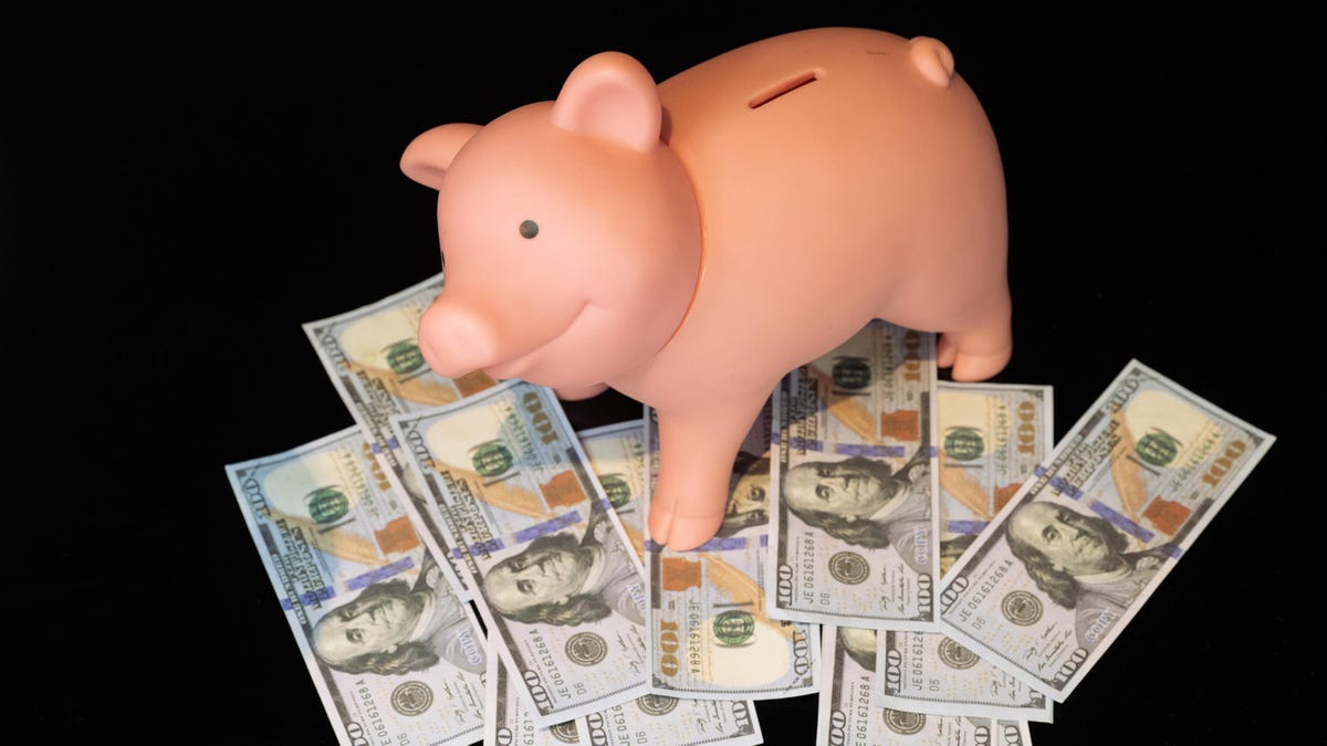 Piggybank standing over $100 bills