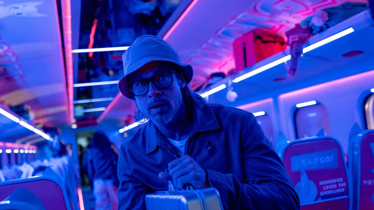Brad Pitt lit in neon blue and pink on a train.