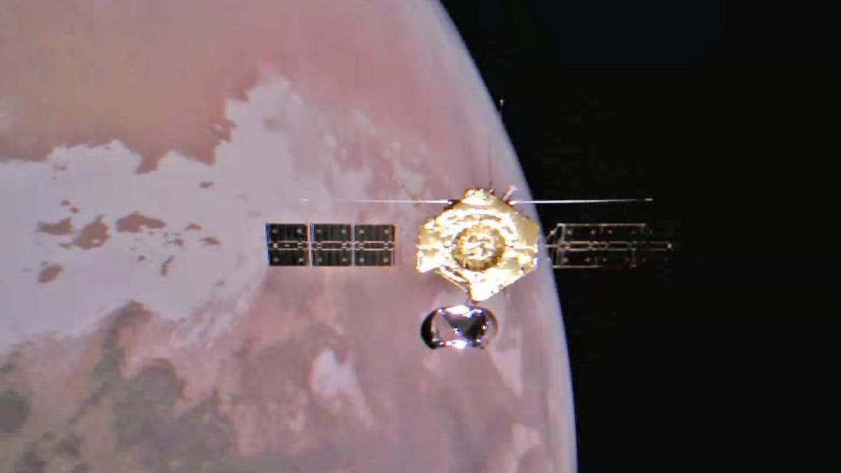 Selfie shot of Tianwen-1 spacecraft, solar panels outstretched, against the reddish backdrop of Mars.