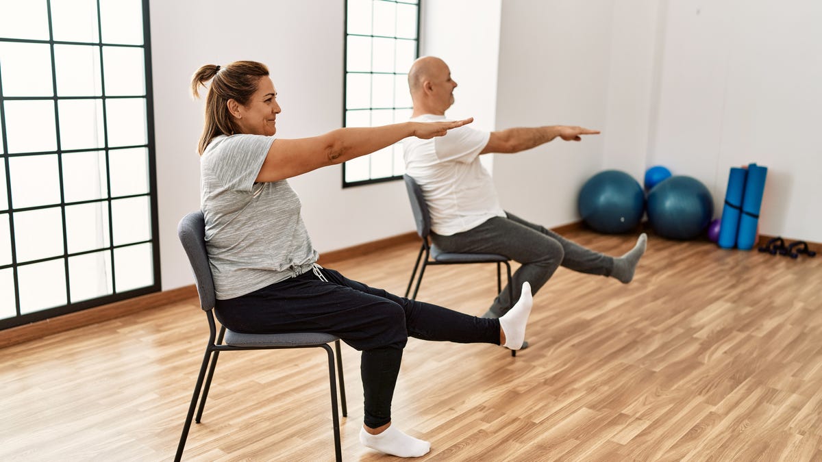 A couple using chairs to stretch and exercise