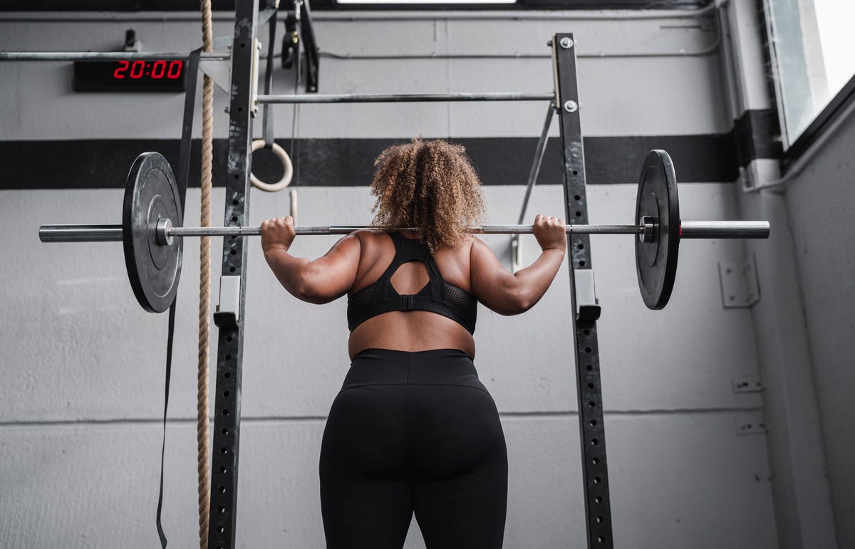 Woman backsquatting barbell with weight plates