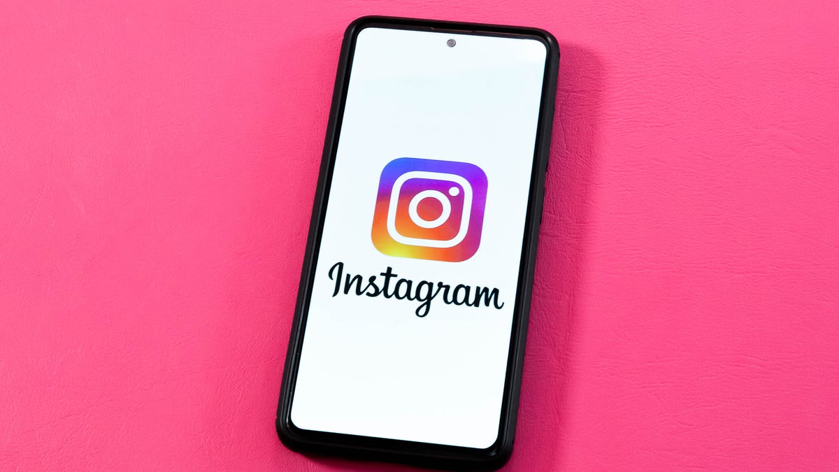 Instagram logo on a phone in front of a pink background