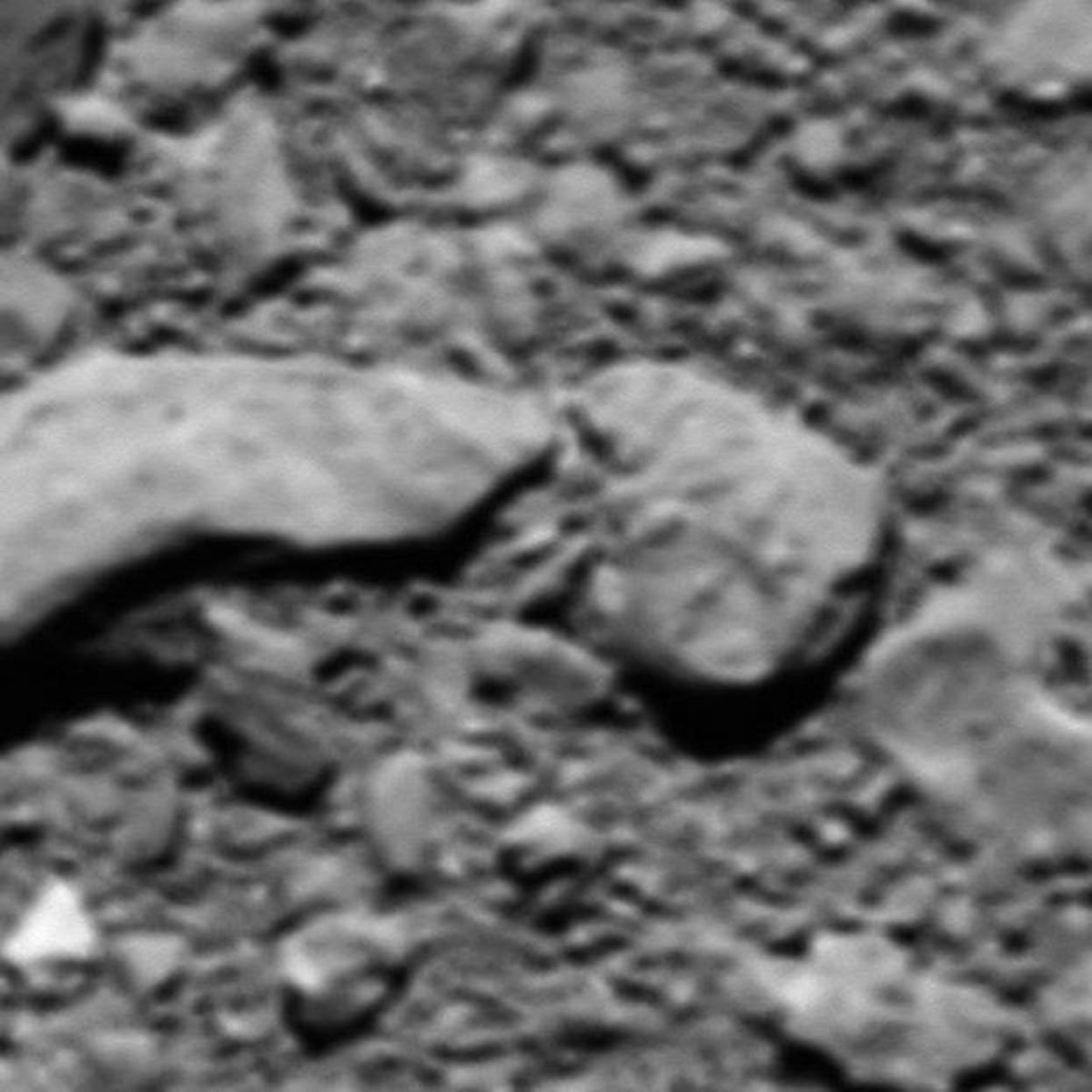 Blurry view of rocks and rubble on the surface of a comet.