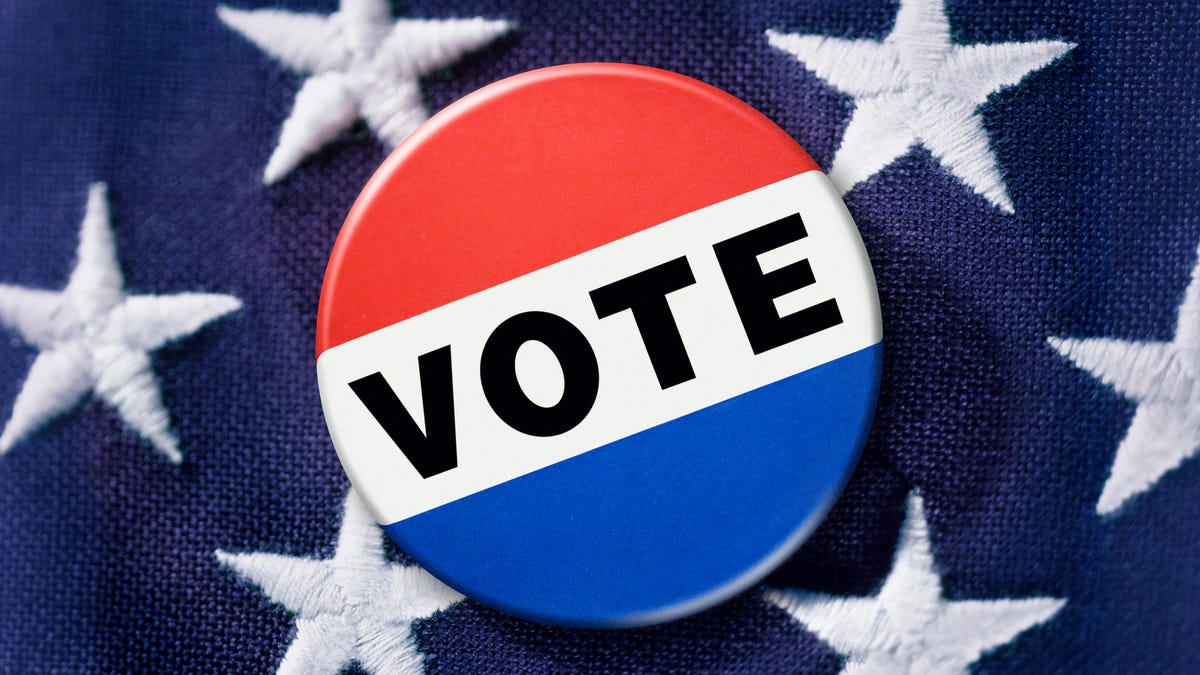 An image of a voting button in front of the stars of the American flag.