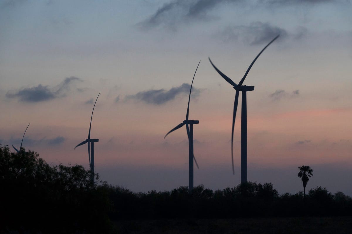 At sunset, silhouetted wind farm turbines produce clean renewable energy near Harlingen, Texas.