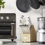 A kitchen counter holds a food processor, a knife set and a Cuisinart Air Fryer Toaster Oven.