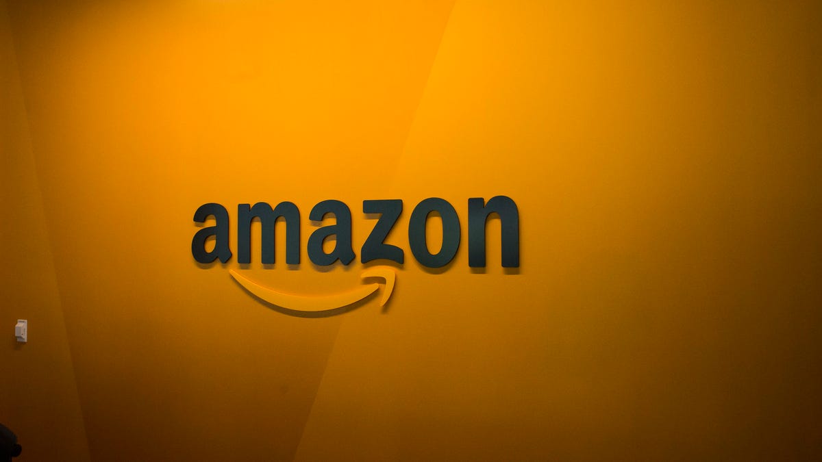The Amazon logo on an orange wall.