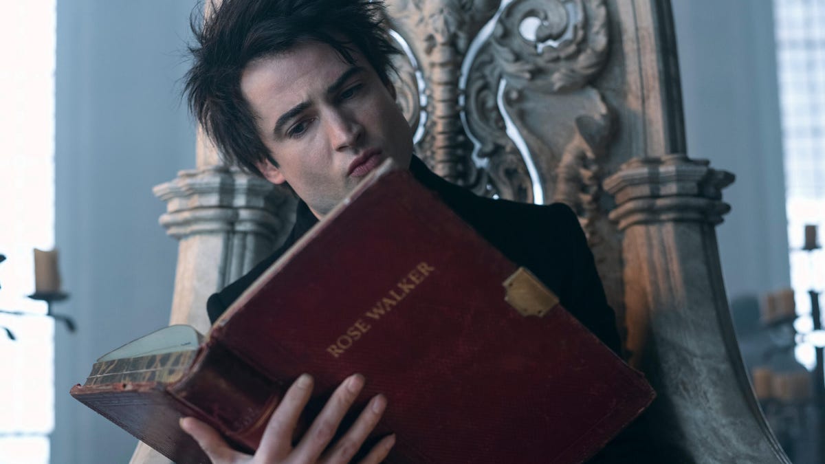 A gothic looking man sits on a throne and reads an ancient book in Netflix fantasy series The Sandman.