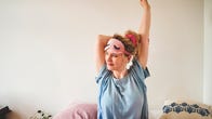 A woman stretching in bed in the morning with a sleep mask
