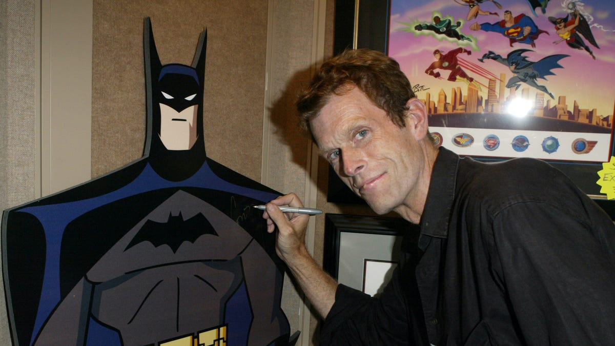 Kevin Conroy leans over to sign a Batman standee