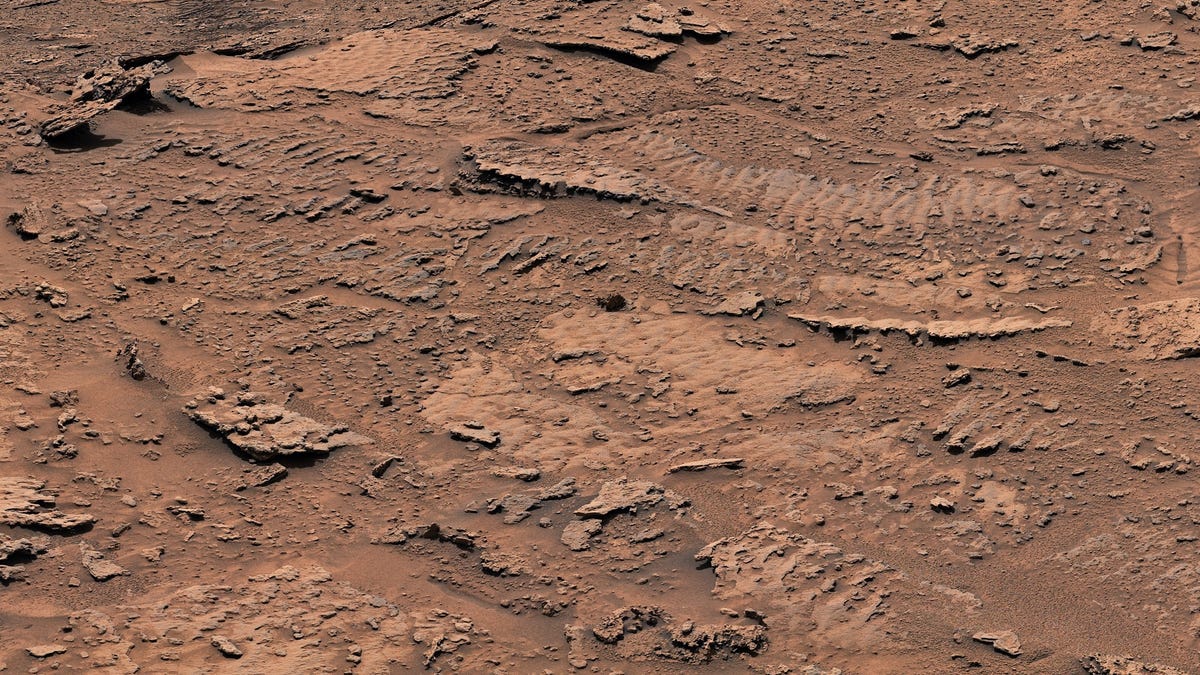 View of reddish-brown Mars ground shows rippling marks NASA attributes to waves in a shallow lake. It looks like a dried bed after water is long gone.