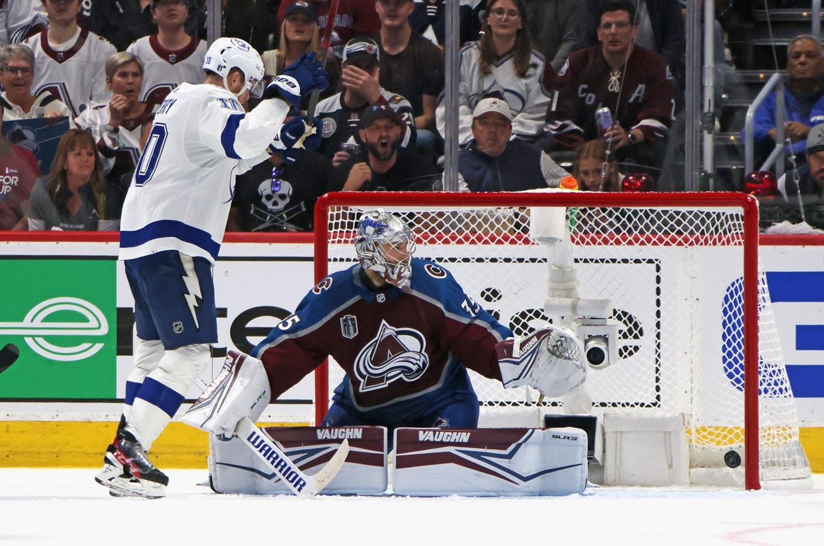 Lightning forward Corey Perry raises his arms in celebration in front of Avalanche goalie Darcy Kuemper after the puck lands in the back of the net.
