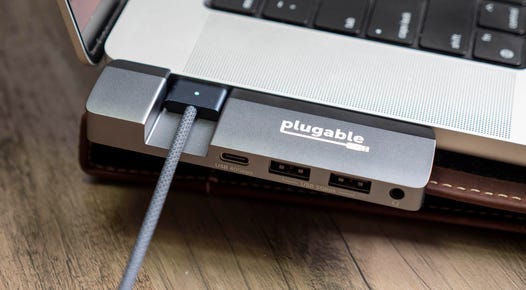 Plugable 5-in-1 USB C Hub with MagSafe support connected to a 16-inch MacBook Pro's USB-C ports on the left side of the laptop.