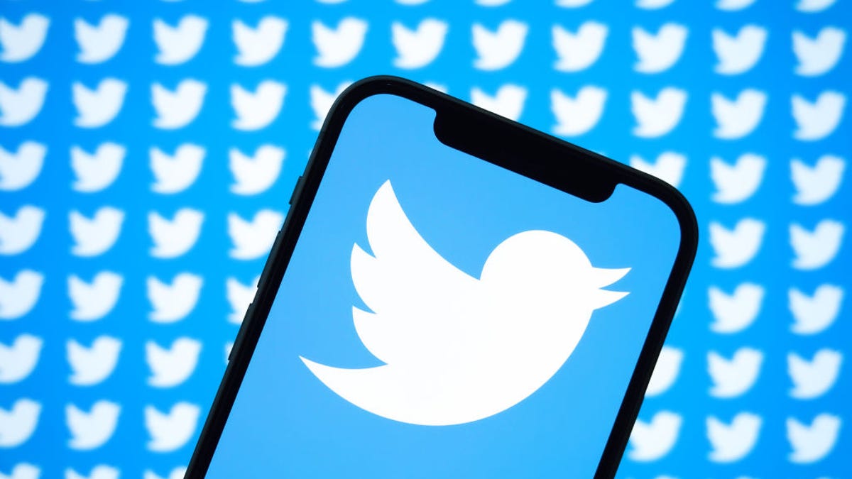 Twitter logo on a phone screen, with a backdrop of multiple Twitter logos