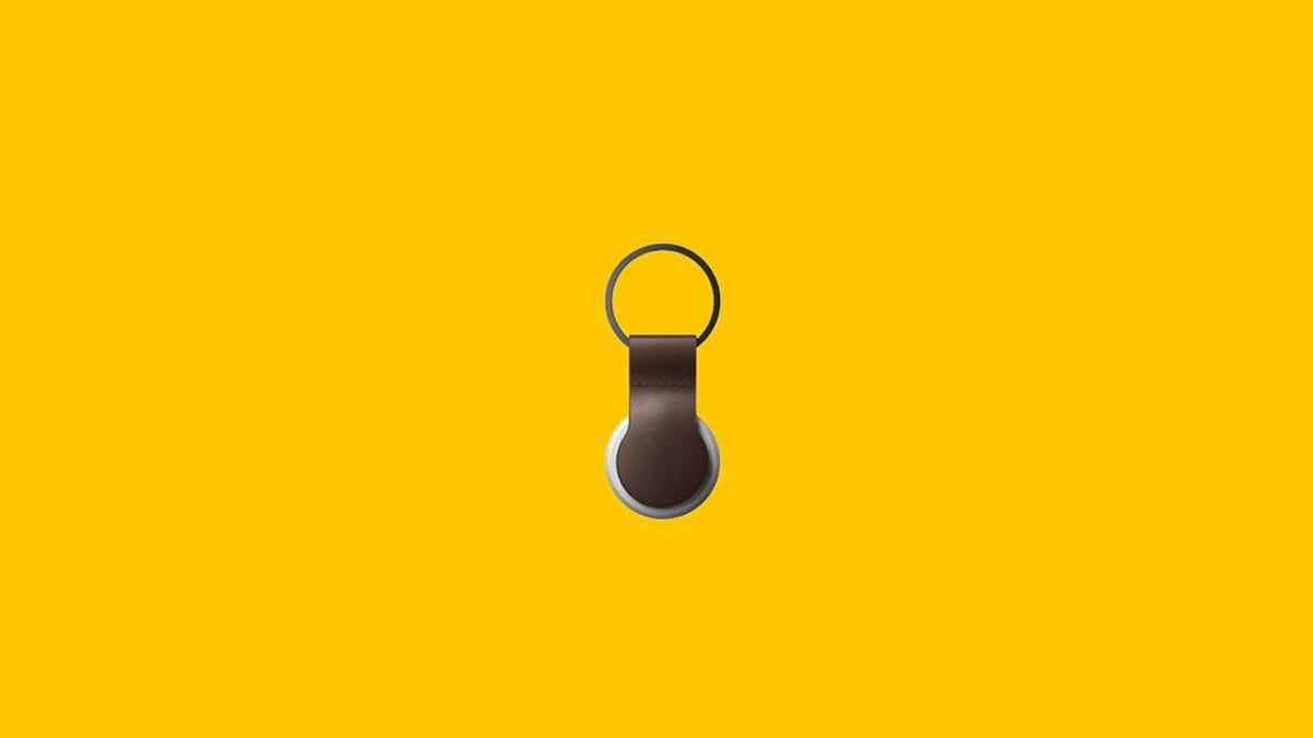 A leather AirTag loop from Nomad with an Apple AirTag attached is displayed against a yellow background.