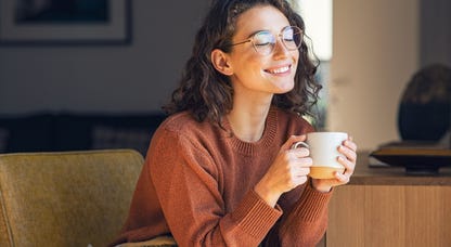 Woman smiling and relaxing while drinking tea.