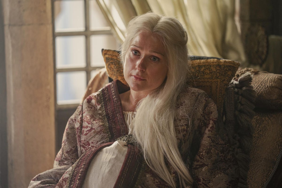 Aemma Targaryen, seated in a chair with pillows, looking weary